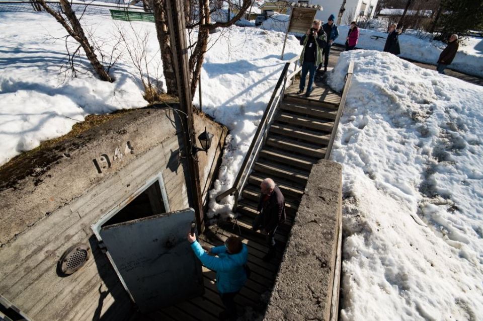 A 1944 bomb shelter entrance with people nearby.