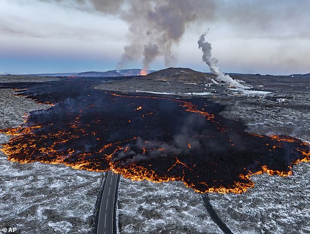 Lava pictured flowing across one of the roads near Grindavik on November 21, 2024 with the Blue Lagoon geothermal spa to the right