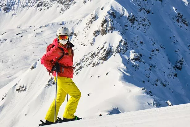 Woman skier with medical mask and colorful clothing in Arosa Lenzerheide ski resort, on a sunny Winter day