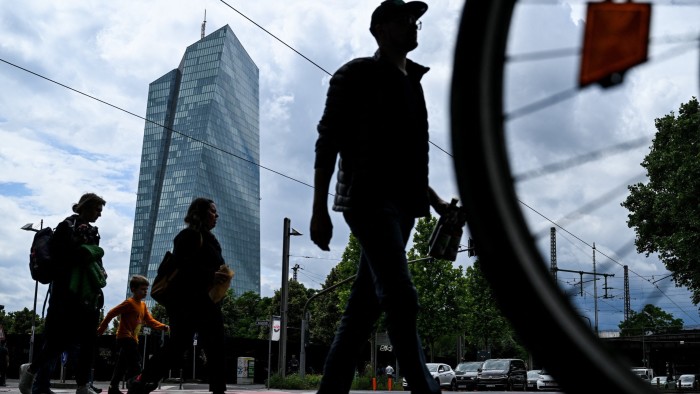 People cross a street in front the headquarters building of the European Central Bank