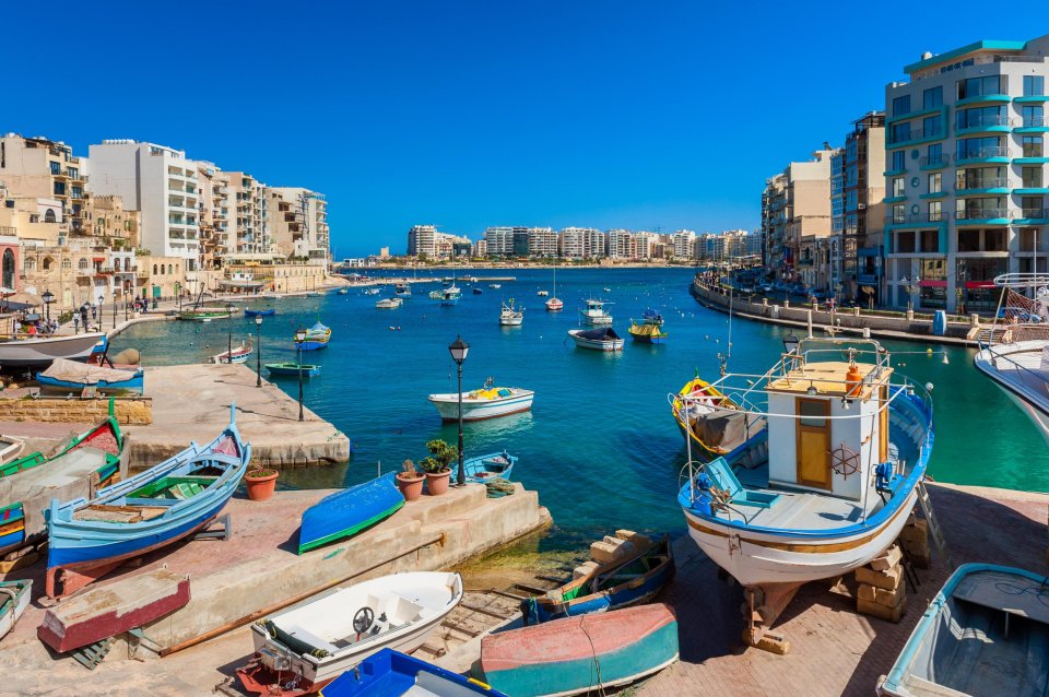 St. Julian's Bay, Malta, with boats in the harbor and buildings along the shore.