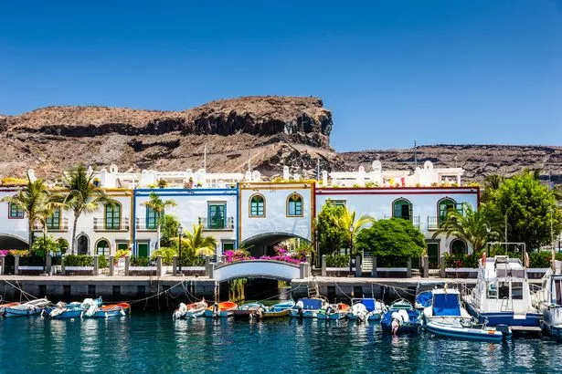 Colorful waterfront houses at the harbor of Puerto de Mogan with small motor boats