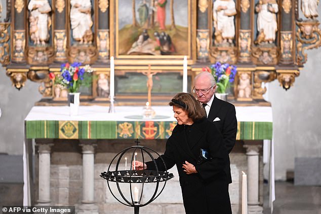 King Carl XVI Gustaf of Sweden (L) and Sweden's Queen Silvia light a candle at the memorial service in the Saint Nicholas church in Orebro, Sweden