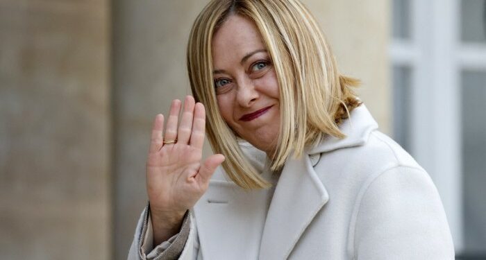 Giorgia Meloni smiles and waves as she arrives at the Élysée Palace in Paris