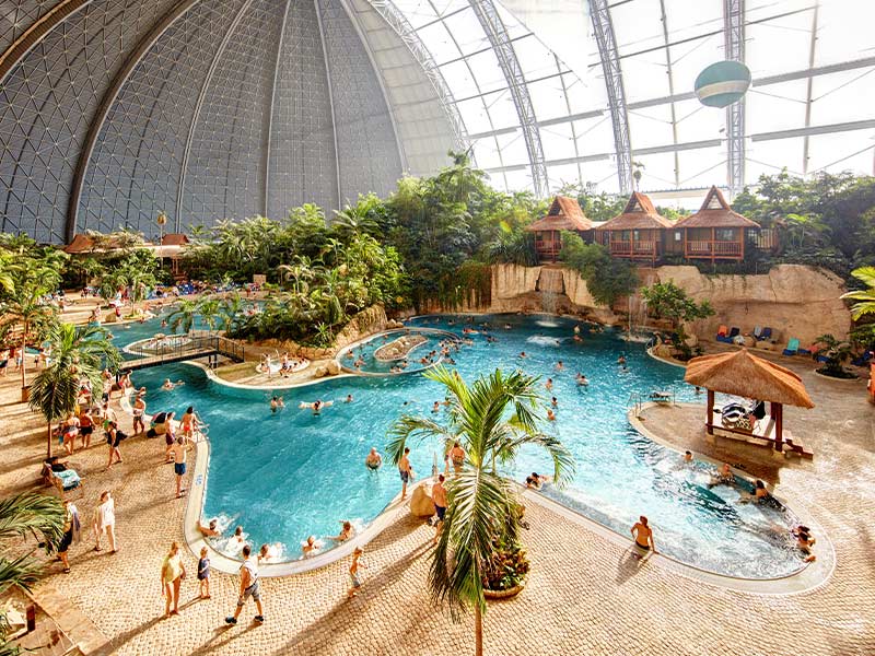 Tropical Islands indoor water park with large pool and tropical landscaping.