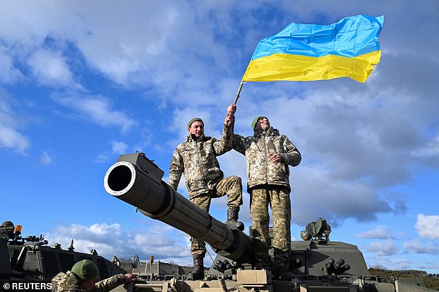 Ukrainian soldiers wave their flag as they stand on a Challenger 2 tank during a training camp in Britain